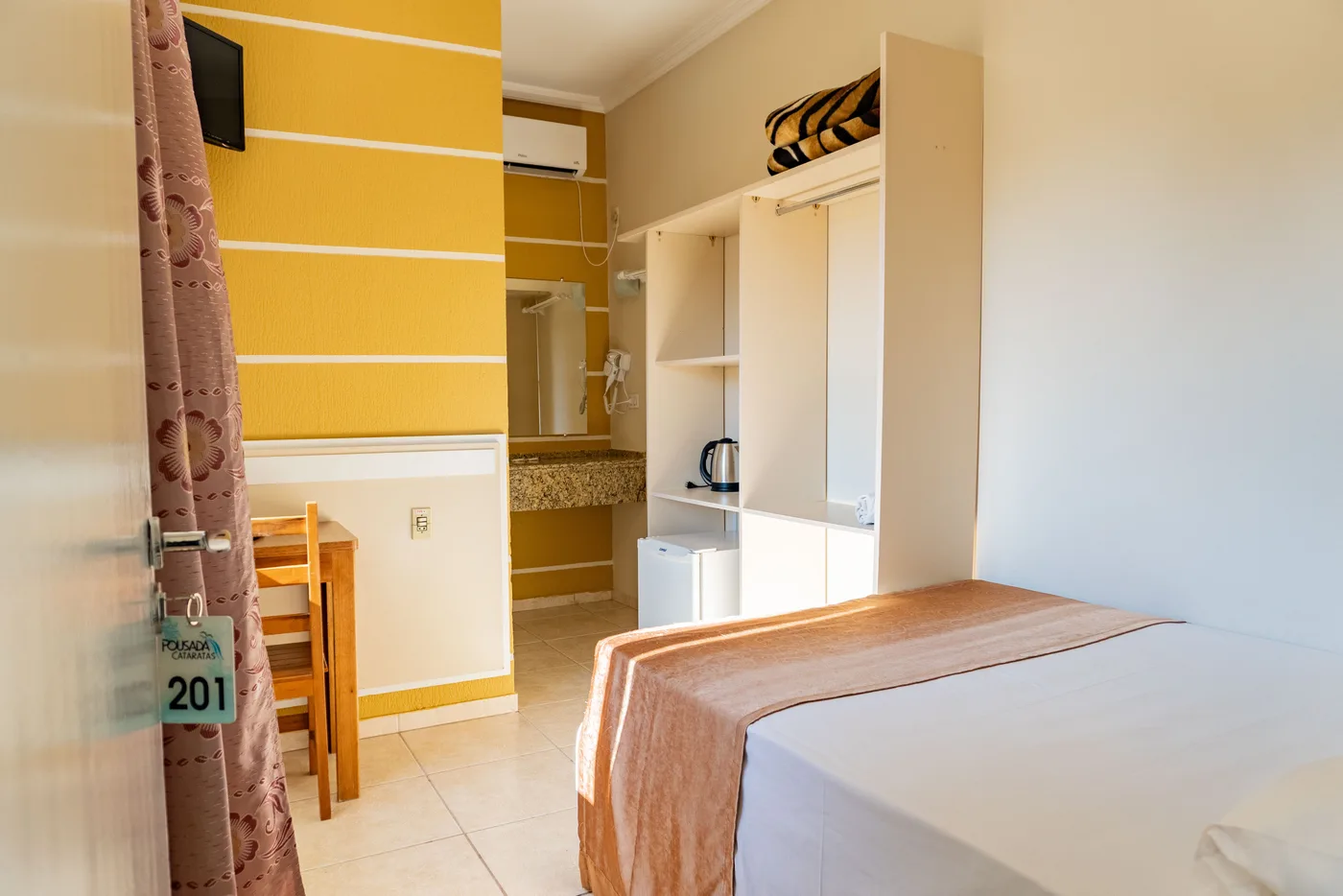 Cama de casal, armário e frigobar do Quarto Duplo da Pousada Cataratas em Foz do Iguaçu